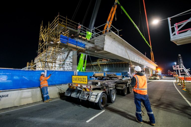 nighttime construction site with men managing the movement of structural beams