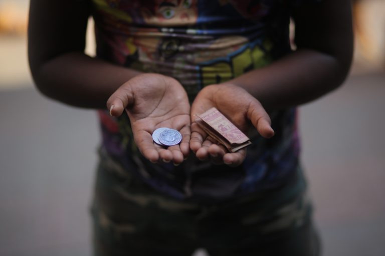 Photo of boy's hands open showing coins and folded bill money